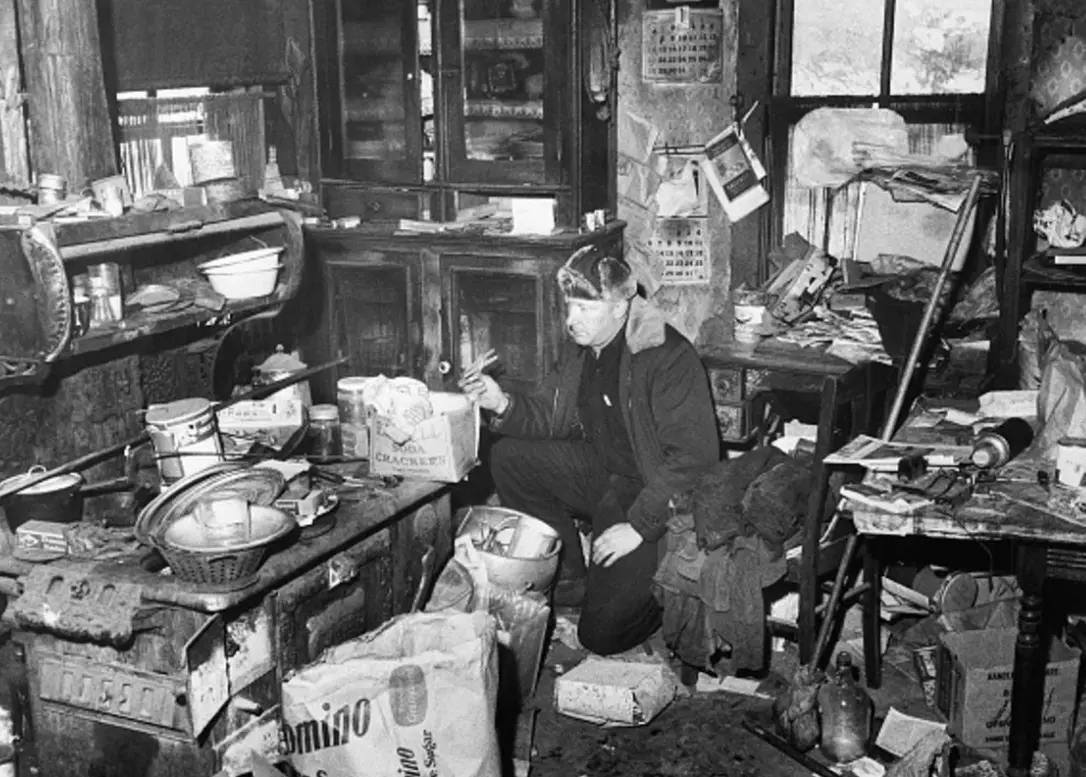 Un agente de policía no identificado examina la cocina llena de basura en la casa de campo de Edward Gein. Especial